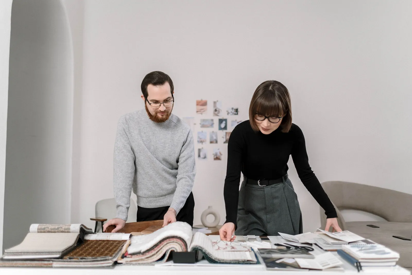 Two people standing at a large table, looking through fabric sample books and swatches together