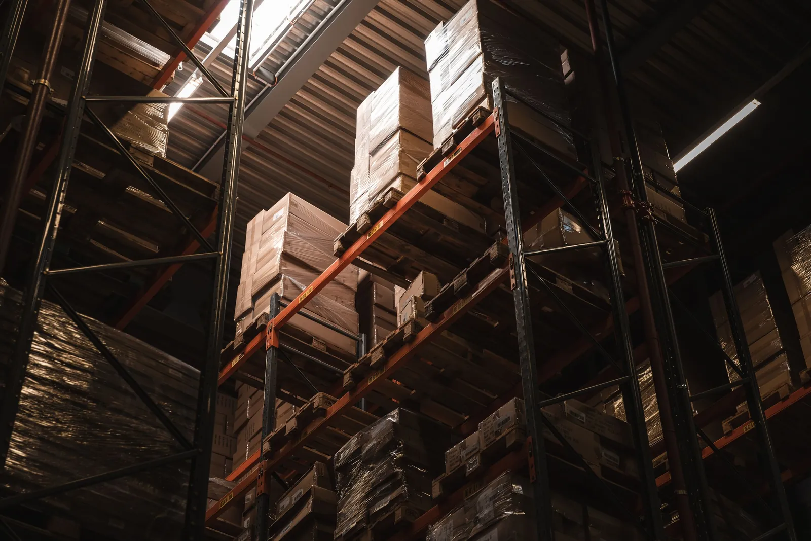 Tall warehouse racks stacked with boxed stock, seen from below