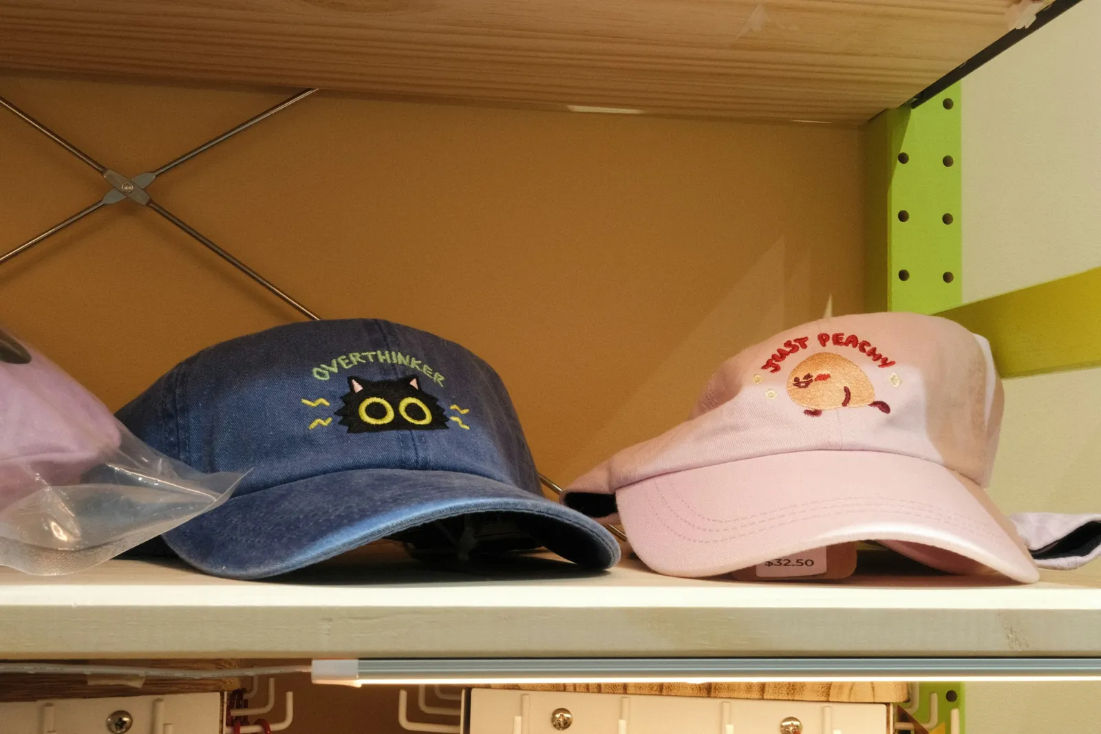 Two embroidered baseball caps, one denim blue and one pink, on a store shelf
