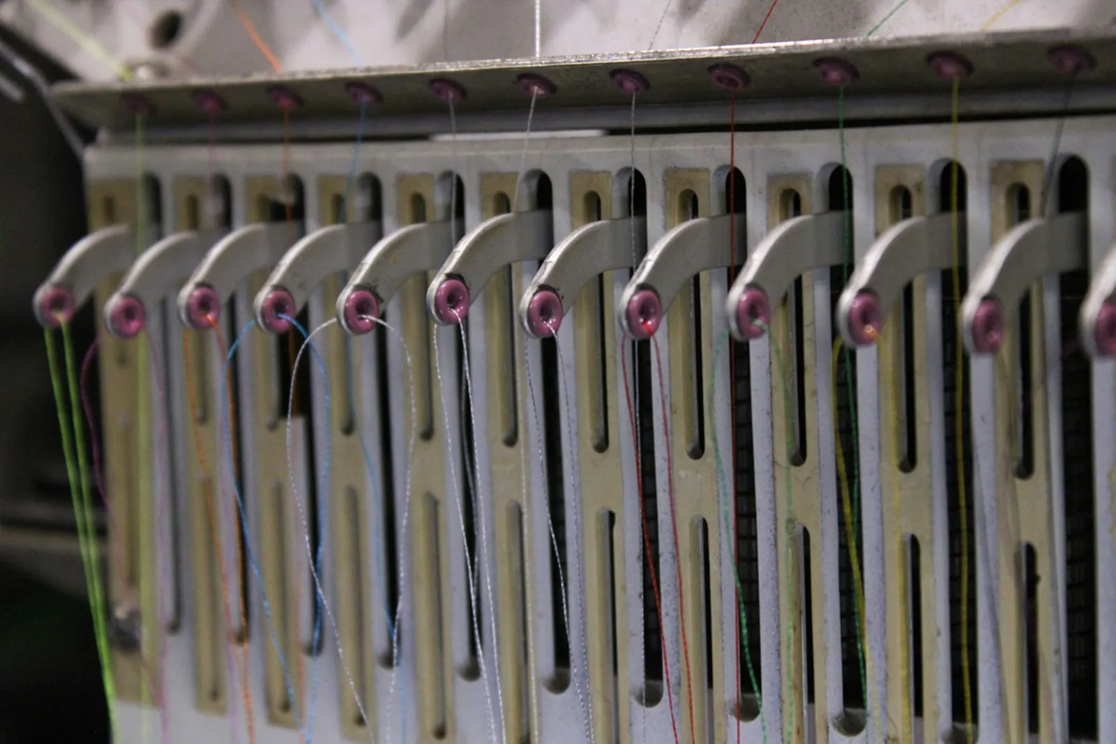 Close-up of the thread guides on a multi-head embroidery machine