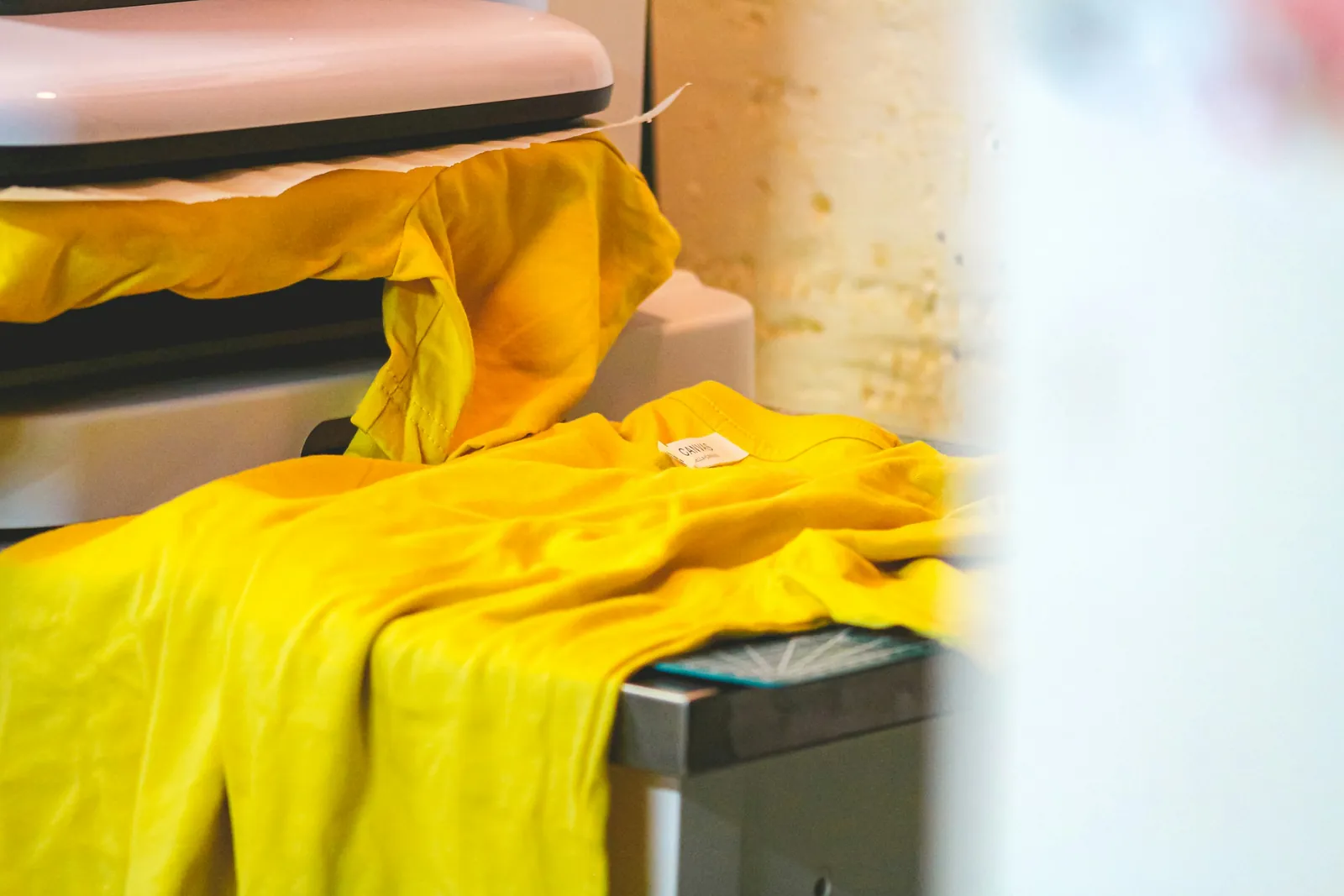 A yellow t-shirt laid out on a heat press