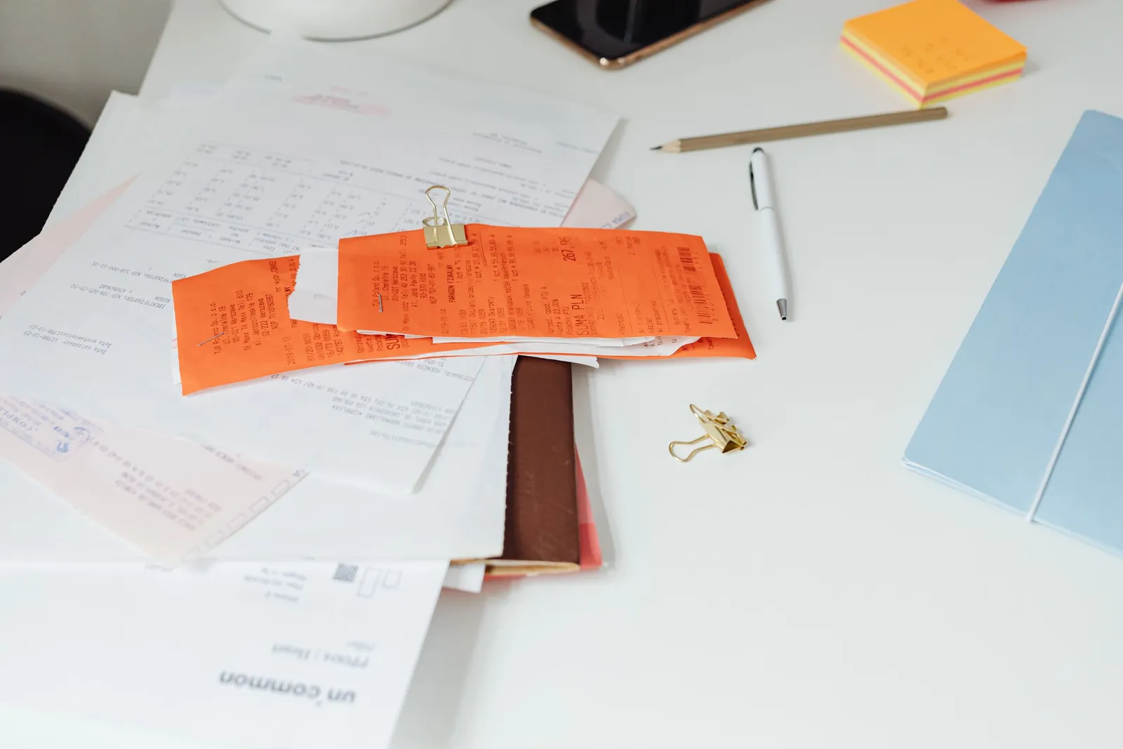 Receipts, invoices and paperwork spread across an office desk