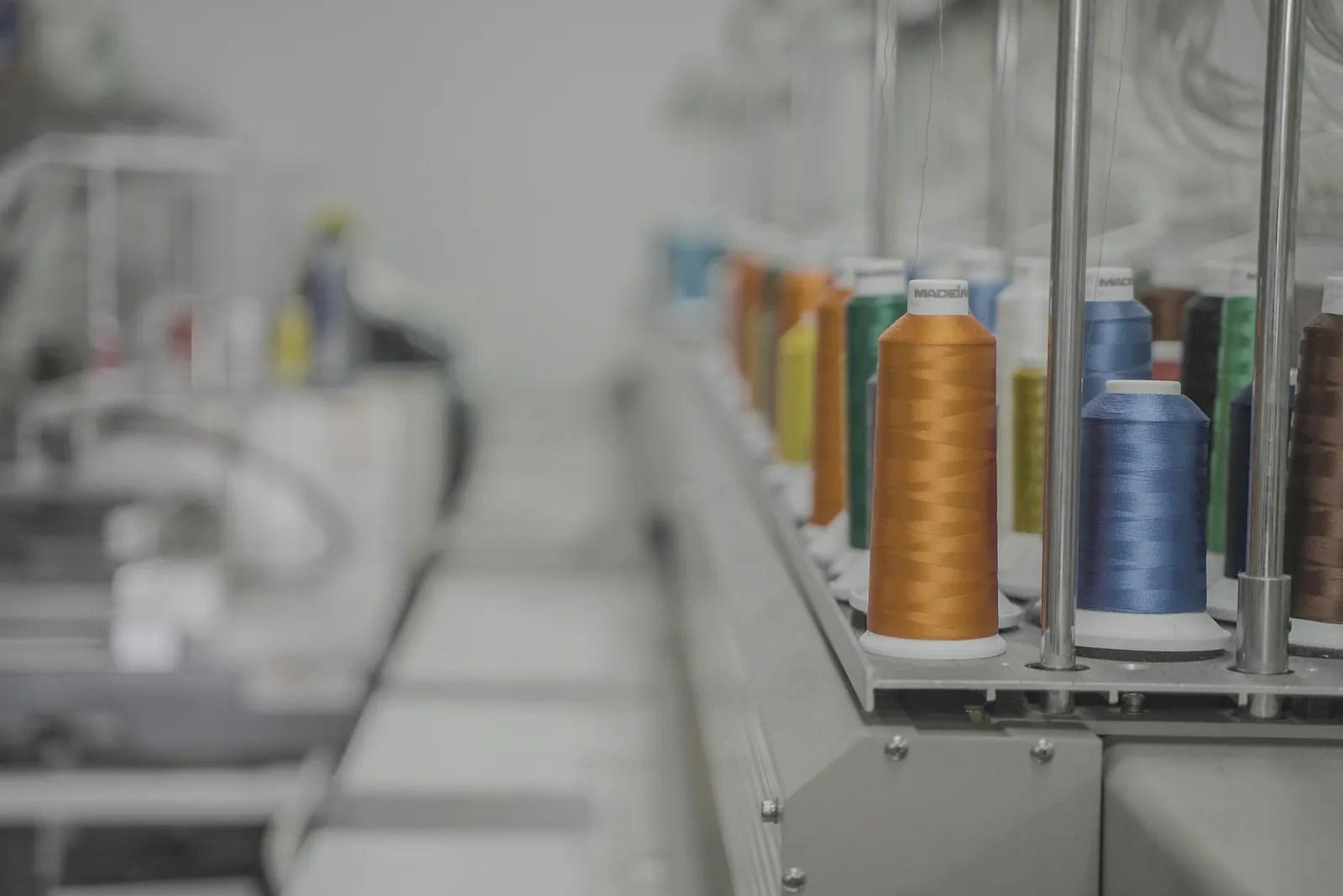 Spools of colored thread lined up on an industrial embroidery machine