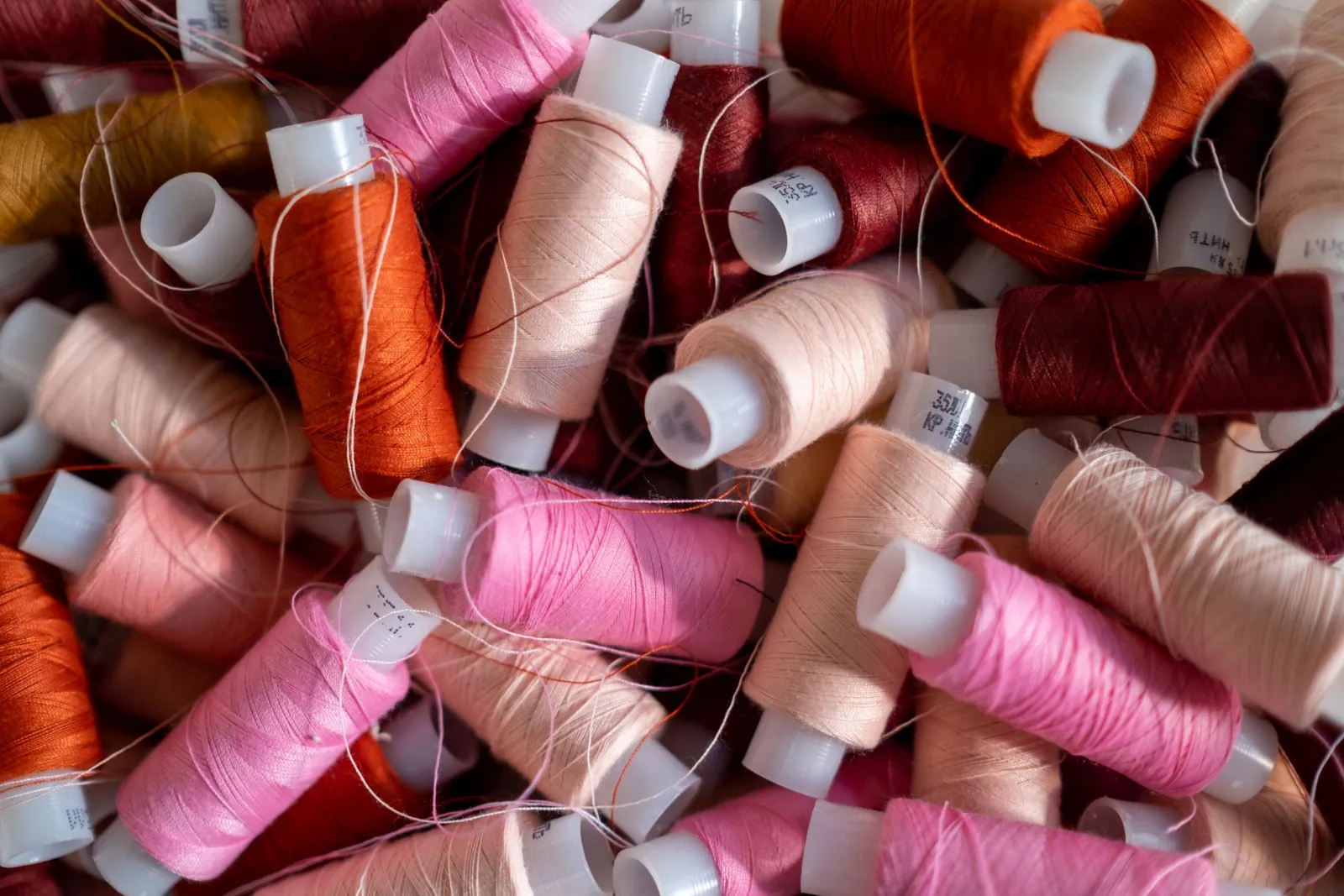 Spools of sewing thread in shades of pink, red and orange