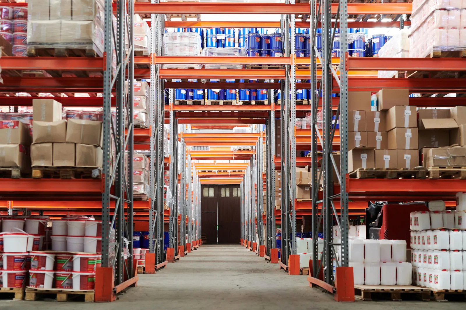 A warehouse aisle lined with tall orange shelving stacked with boxes and stock
