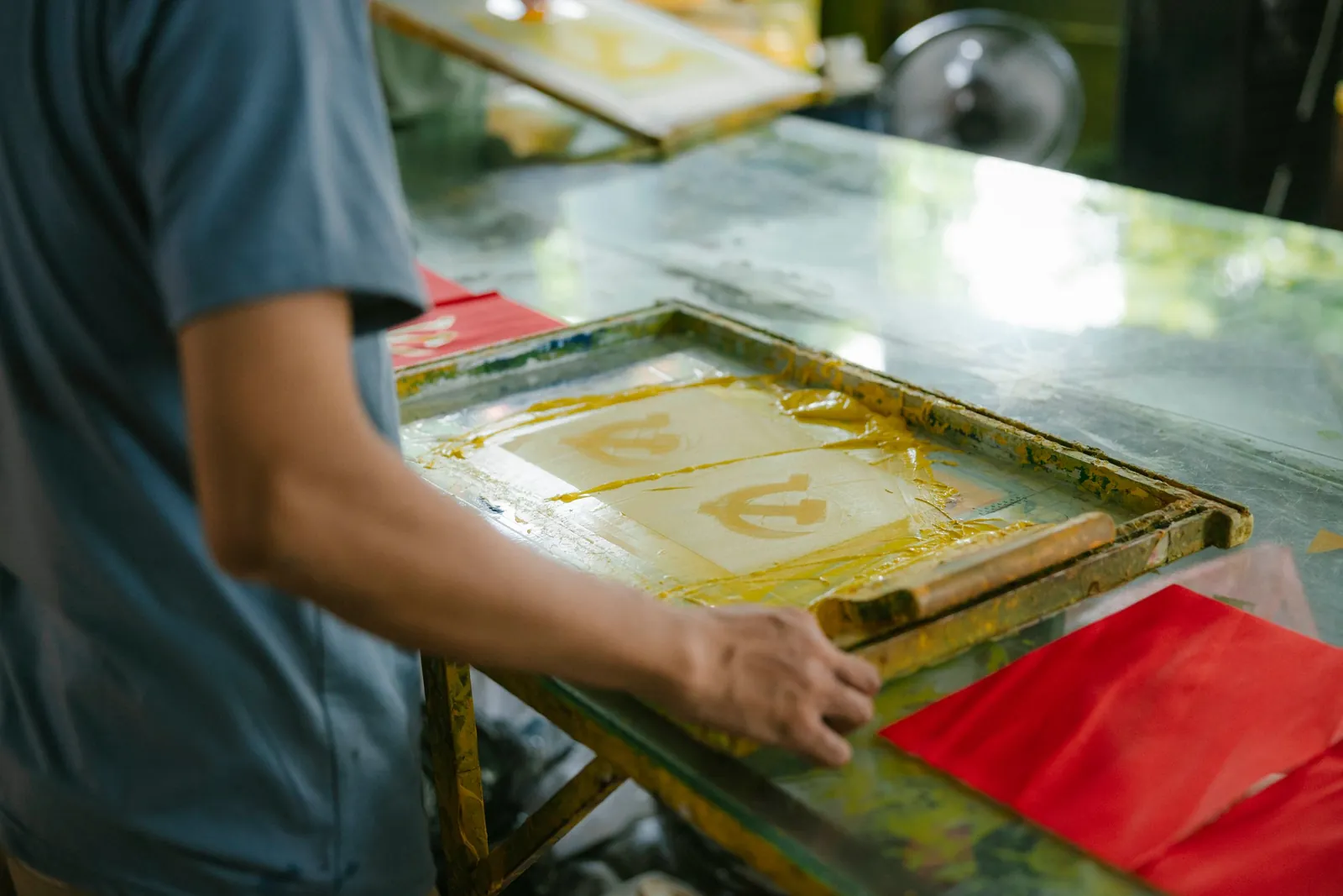 A screen printer pulling yellow ink through a screen by hand