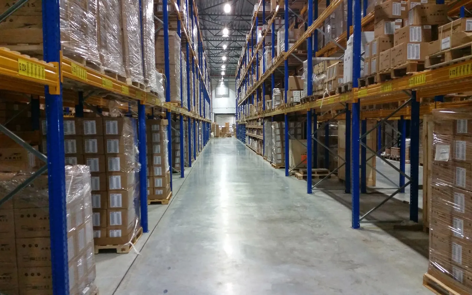 A long warehouse aisle with tall shelves stacked with cardboard boxes